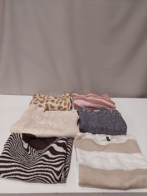 several sweaters and scarves laid out on a white table