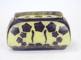 a yellow and black vase with black flowers on it