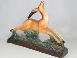figurine of a running deer with a bird in its mouth