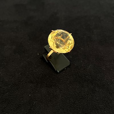 bague en diamant jaune posée sur un socle noir, sur une surface noire