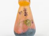 un petit vase sur lequel sont peintes des fleurs sur un fond blanc