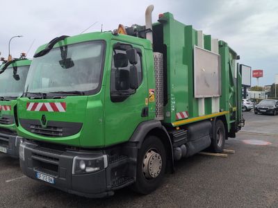 a green garbage truck that is parked in a parking lot