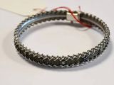 silver bracelet with a red string on it sitting on a white surface