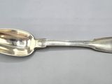 silver plated spoon with ornate design on it on a gray surface