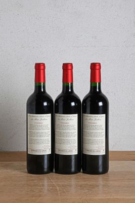 three bottles of wine sitting on a wooden table next to a bottle of wine
