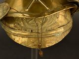 a gold helmet on a stand with a necklace on it