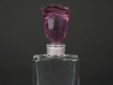 une petite bouteille en verre ornée d'une fleur rose