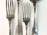 four spoons and two forks on a white surface
