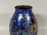 un vase bleu posé sur une surface blanche