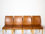 three brown leather chairs sitting on top of a white surface