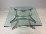 une table en verre avec une base en métal et un plateau en verre