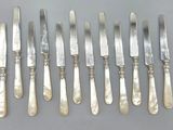 six couteaux argentés et six couteaux posés sur un support gris