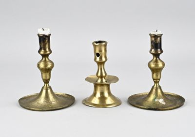 trois bougeoirs en laiton posés sur une surface blanche, sur fond blanc