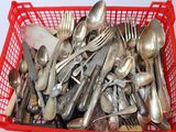 un panier rouge rempli de cuillères en argent et de cuillères