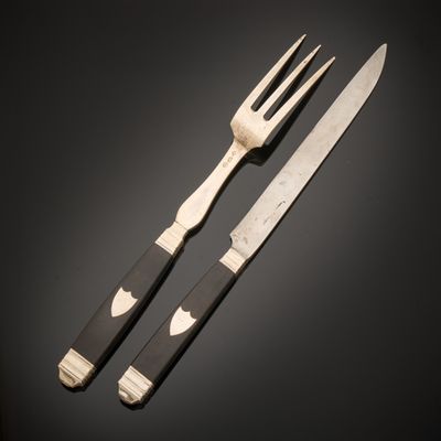 two forks and a knife on a table with a black background