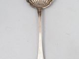 une cuillère ancienne en argent posée sur une surface blanche, avec un manche en argent