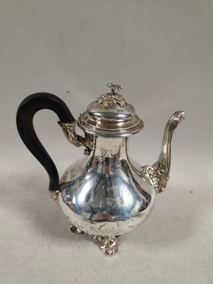 une théière ancienne en argent avec une poignée noire sur une surface blanche