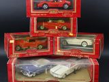 three boxed red and white toy cars in boxes on a black background