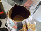 un vase en argent posé sur une table, à côté d'une bouteille de vin