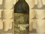 une bouteille de vin posée sur une table devant un mur de tasses