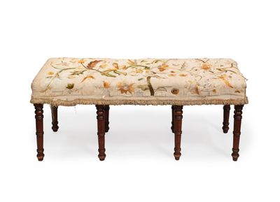 un banc rembourré sur lequel repose un coussin à motifs floraux