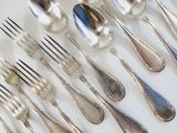 a lot of silver spoons and forks on the table