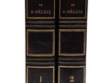 two black books with gold trims are stacked on top of each other