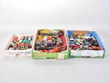 Deux boîtes contenant un assortiment de petits véhicules jouets sont posées sur une surface blanche.