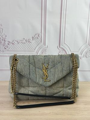 un petit sac gris muni d'une chaîne dorée, posé sur une table en bois