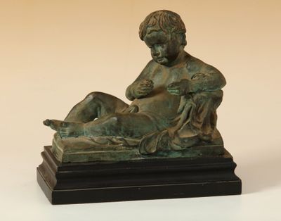 statue en bronze représentant un garçon avec un chien sur les genoux
