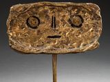 a close up of a sculpture of a face on a wooden base