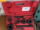 une boîte à outils rouge contenant des outils, posée par terre