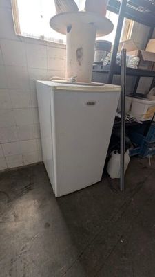 un petit réfrigérateur blanc dans une pièce où se trouve une échelle