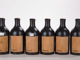 six bouteilles de vin sont alignées sur une surface blanche