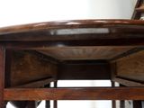 a close up of a wooden table with a chair in the background