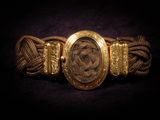 a close up of a gold bracelet with a picture of a woman on it
