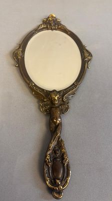 miroir posé sur une table, avec un cadre doré et un fond blanc
