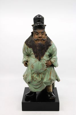 statue d'un homme barbu et coiffé d'un chapeau, assis sur un socle noir