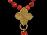 un collier composé de perles dorées et corail, orné d'un pendentif en forme de fleur