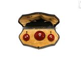 three red balls in a case on a white surface