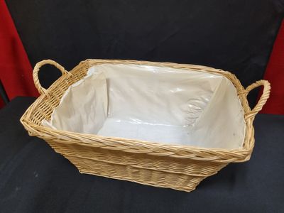un panier en osier vide muni de poignées, sur fond noir