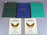 three books on a table with a butterfly on top of them