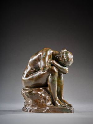 une statue en bronze représentant un homme assis sur un rocher, la tête entre les mains
