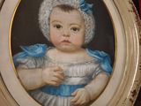 un tableau représentant un bébé vêtu d'une robe bleue et d'un bonnet
