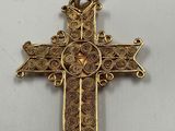 a gold cross on a white table with a white background
