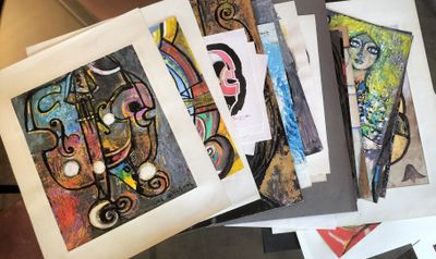 a lot of paintings on a table with papers on it