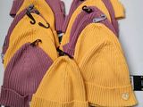 six pairs of yellow and purple knitted hats with tags on them