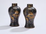 two black vases with gold designs on them on a table