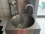 a stainless steel sink in the middle of a tiled floor