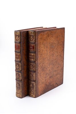 two old books sitting on top of each other on a white surface